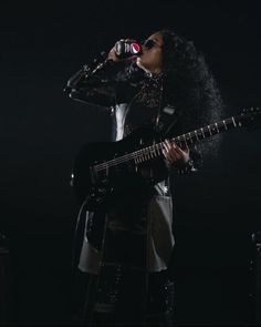 a woman singing into a microphone while holding a guitar