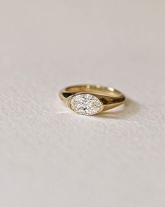 a gold ring with a single diamond in the center on a white tablecloth background