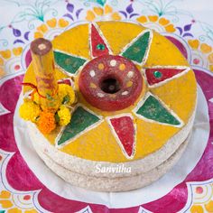 there is a decorated cake with flowers on the tablecloth and an orange candle next to it