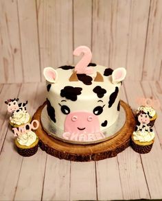 a birthday cake with cupcakes and a cow on the side that says 2