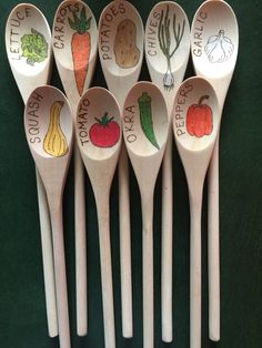 six wooden spoons with different types of vegetables painted on them, lined up in a row