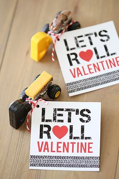 two valentine's day cards on a wooden table with toy trucks and rubber stamps