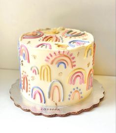 a white cake decorated with rainbows and clouds