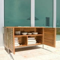 a wooden cabinet with glass doors and bowls on it's shelf next to a swimming pool