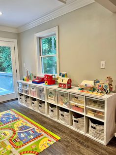 a child's playroom with toys on the floor and storage bins next to it