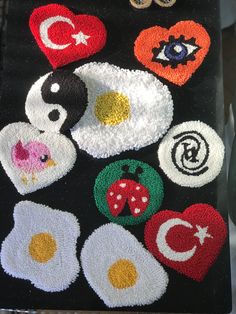 an assortment of embroidered patches and buttons on a black cloth with white, red, green, orange, and yellow designs