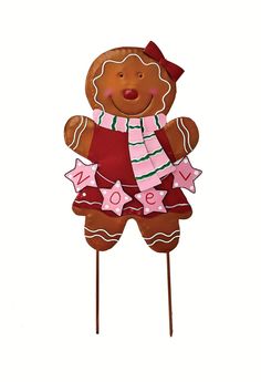 a brown teddy bear standing on top of a wooden stick wearing a pink and white scarf