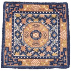 a blue and yellow rug with an intricate design on the center, surrounded by smaller squares