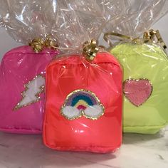 three small bags with sequins on the handles and one has a rainbow in it