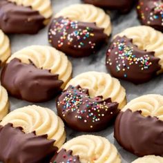 chocolate covered cookies with white frosting and sprinkles on a baking sheet