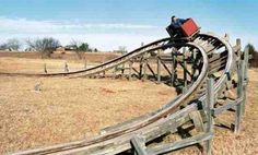 a person riding a roller coaster in the middle of an open field with brown grass