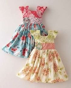 two dresses hanging on the wall next to each other, one in blue and one in pink