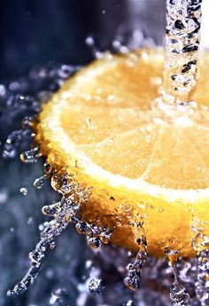 an orange being washed in water with a faucet