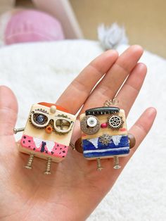 two small figurines in the palm of someone's hand, one is wearing glasses