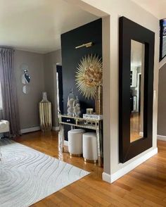 a living room filled with furniture next to a mirror on the wall and wooden floors