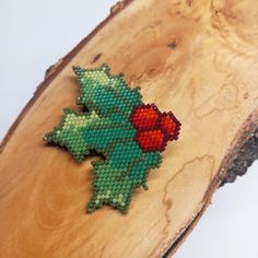 a piece of bead art with a holly on it sitting on top of a wooden slab