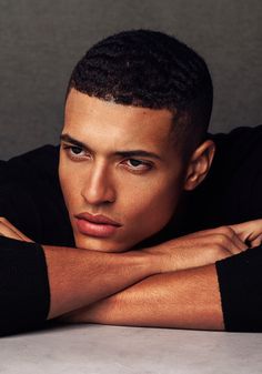 a close up of a person leaning on a table with his arms crossed and looking at the camera