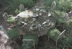 an aerial view of a table and chairs set up for a meal in the woods