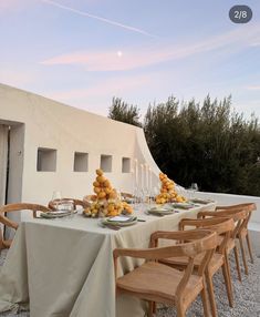 an outdoor dining table set with food and wine glasses