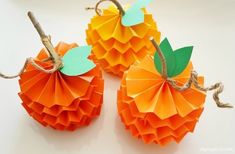 three orange paper pumpkins with leaves on them