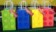 small lego bags with name tags on them are lined up against a green tablecloth