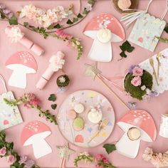 a pink table topped with lots of cupcakes and other items on top of it