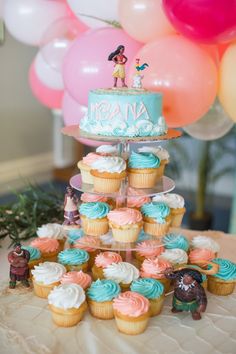 a cake and cupcakes on a table with balloons