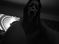 a man with his mouth open wearing a ghost mask in front of a light painting