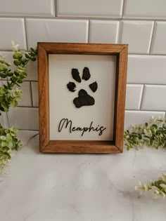 a wooden frame with a dog's paw and name in black ink on it