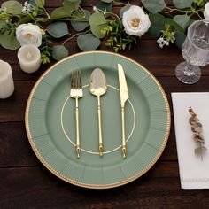 a green plate with gold trim and silverware on it, surrounded by greenery