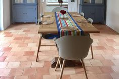 a dining room table and chairs in front of a window with blue cabinets behind it