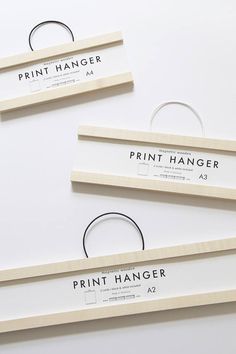 three wooden hangers with print hanger labels attached to them on a white surface