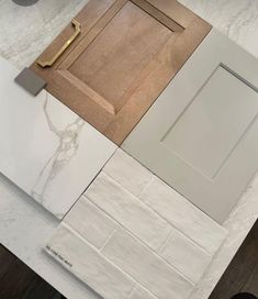 a kitchen counter top with white marble and wooden cabinet doors on each side, next to a door that has a gold handle