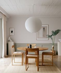 a dining room table with two chairs and a round light fixture hanging from the ceiling