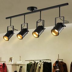 three lights are hanging from the ceiling in a clothing store