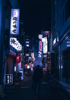 a man walking down an alley way at night with neon signs on the buildings behind him