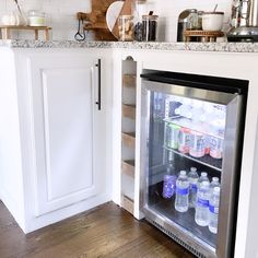 an open refrigerator in a kitchen with lots of bottles on the door and shelves above it