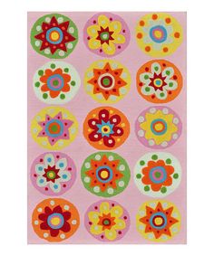 a pink rug with colorful flowers and circles on the front, in various sizes and colors