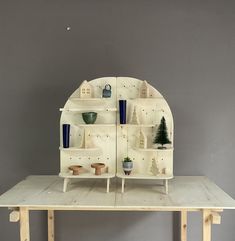 a wooden table topped with shelves filled with vases and potted plants on top of it