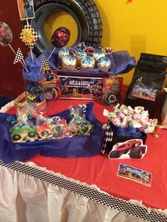 a red table topped with lots of cupcakes and cake covered in frosting