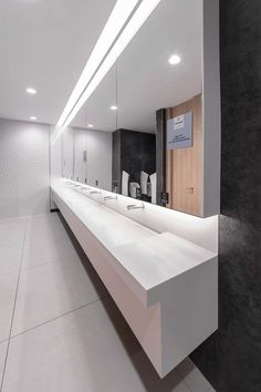 a long counter with sinks and mirrors in a bathroom