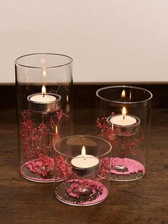 three glass vases with candles in them on a table