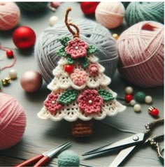 a crocheted christmas tree ornament surrounded by balls of yarn and knitting needles