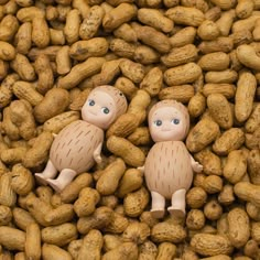 two small dolls sitting on top of peanuts