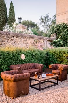 a living room with couches and chairs in the middle of graveled area next to stone wall