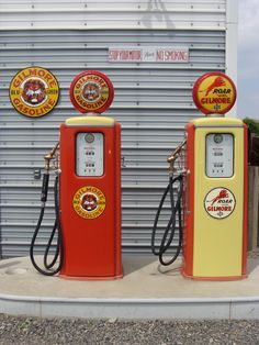 two red and yellow gas pumps sitting next to each other in front of a garage