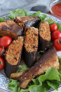 some food is on a plate with lettuce, tomatoes and other foods around it