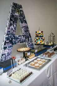 a table topped with cakes and cupcakes next to a letter shaped cake stand