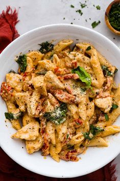 a white bowl filled with pasta and spinach