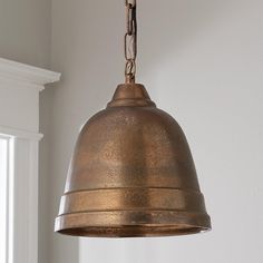 an antique brass pendant light hanging from a white wall